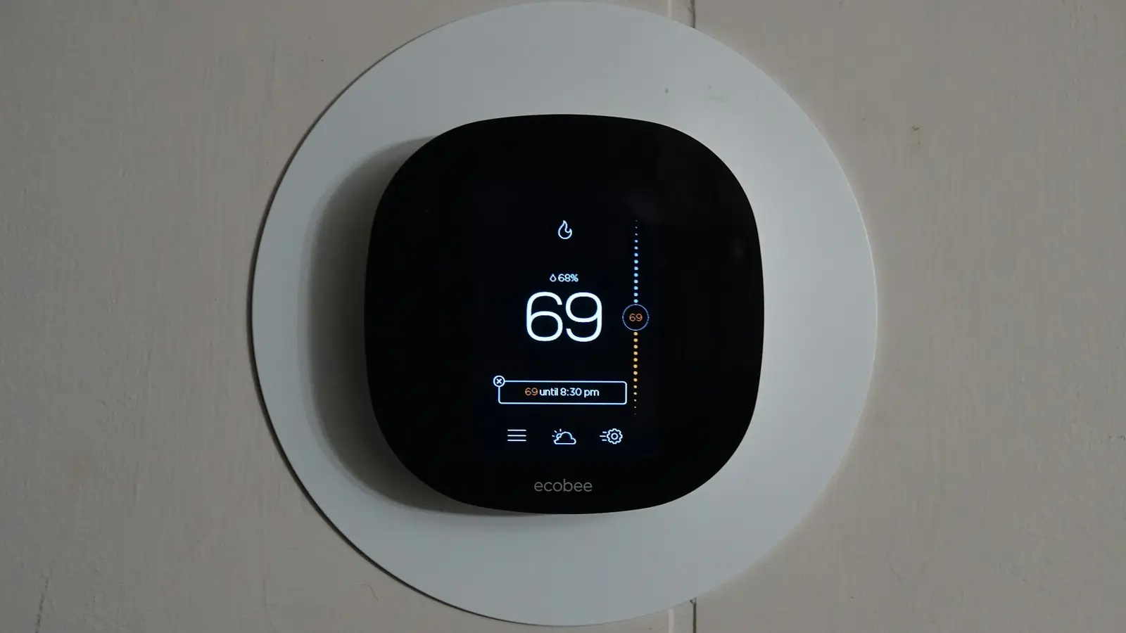 Wall-mounted smart thermostat displaying the current room temperature